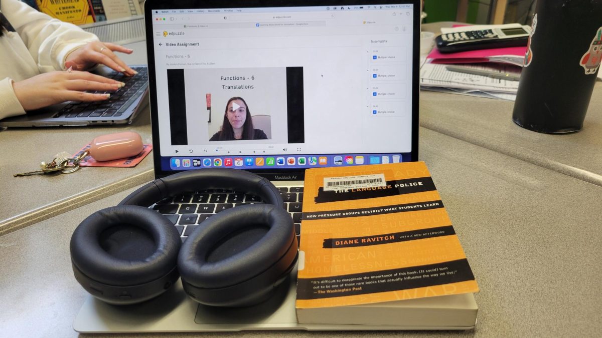 One of Formans Ed Puzzle assignments (visual, auditory) is seen on a laptop screen behind a pair of headphones (auditory) and a book (reading/writing style).